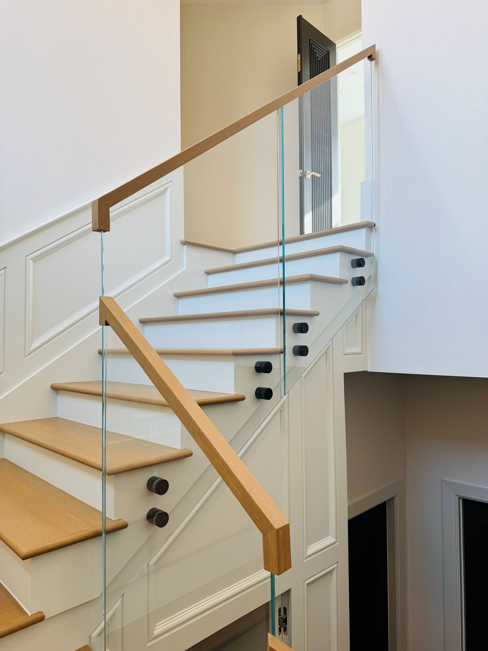 Glass railing with natural wood handrail on a traditional staircase